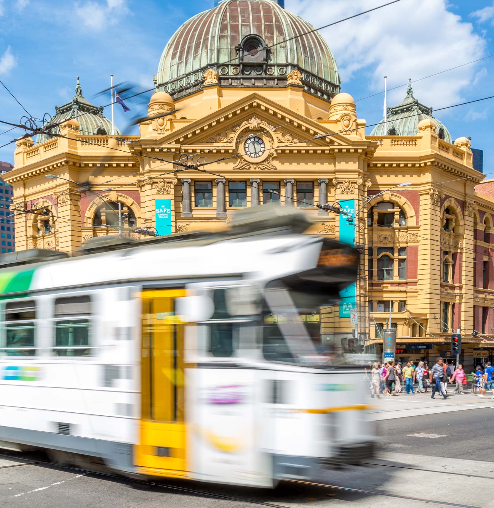A tram in motion travelling past Flinders Street Station.