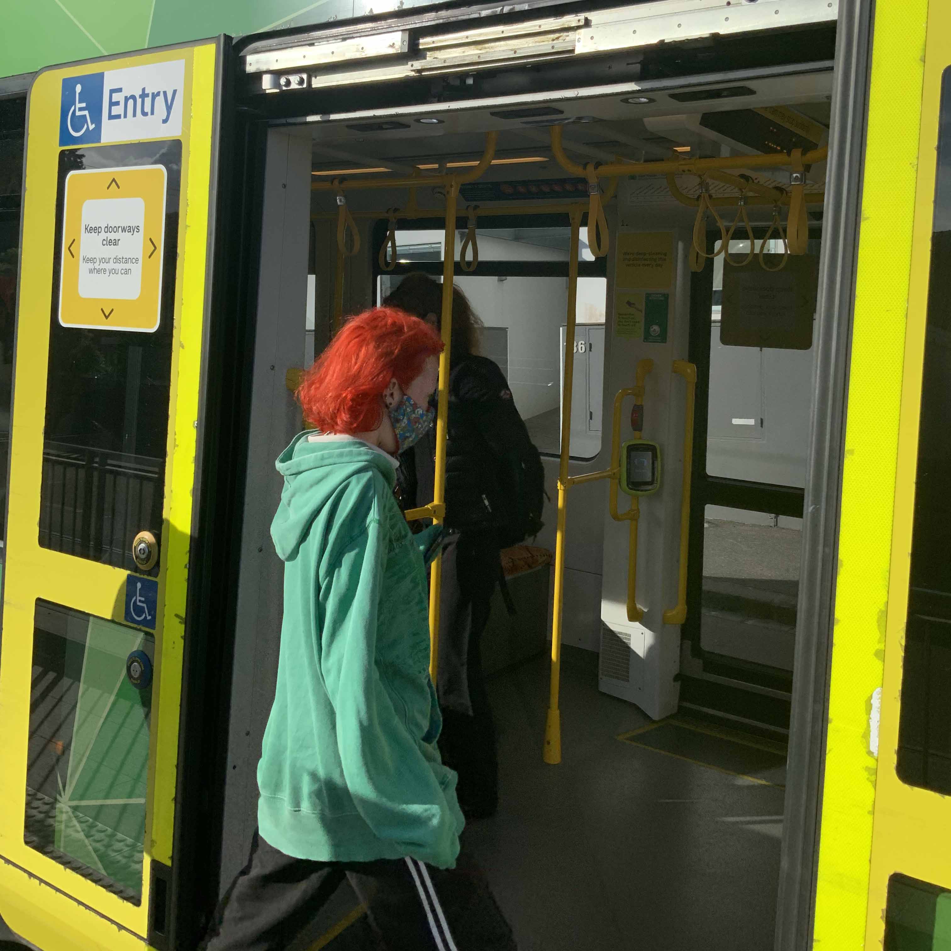 Image shows a person wearing a mask boarding a tram during the COVID-19 pandemic.