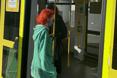 Image shows a person wearing a mask boarding a tram during the COVID-19 pandemic.