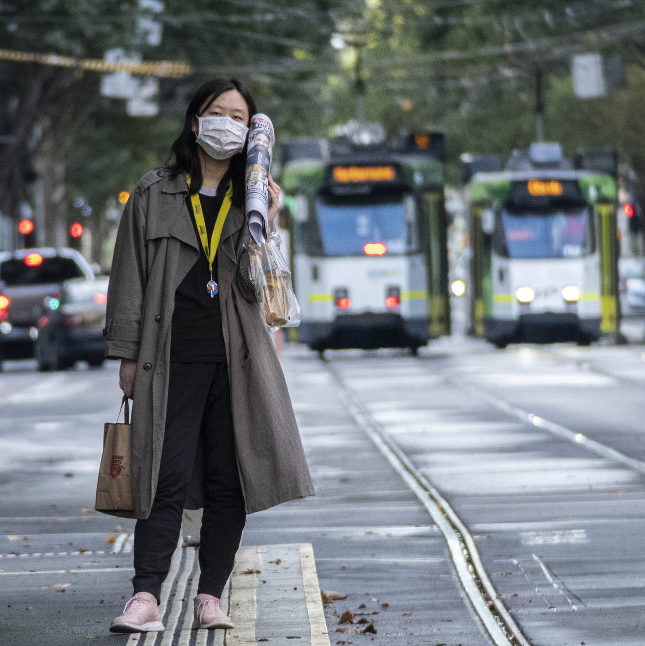 Image shows a person wearing a face mask while waiting at a tram stop during the COVID-19 pandemic.